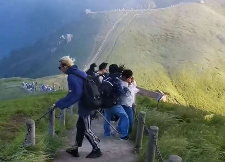 抓着步道铁链抵御狂风的驴友